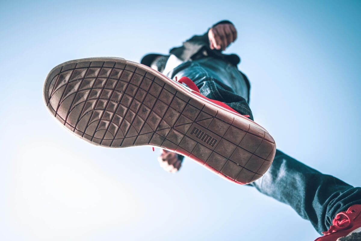 a view from below of a man wearing red puma shoes, with the focus on the puma logo on the sole of the shoe
