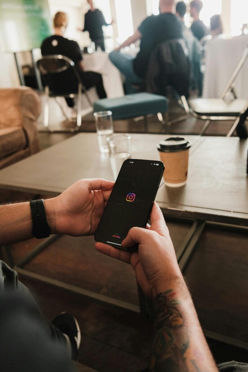 aerial view of a man on his phone on the instagram app, with the out of focus background of a coffee shop