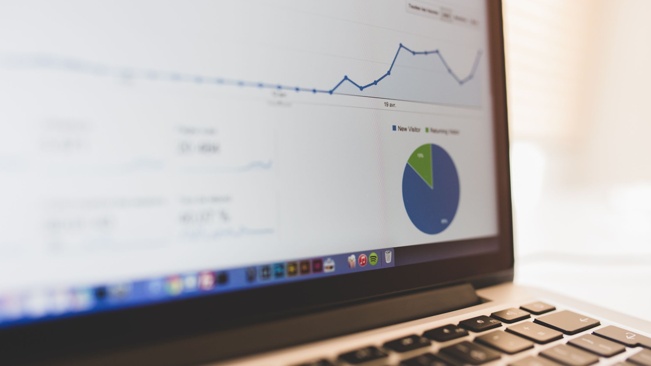 Google Analytics dashboard on a laptop screen showing a line graph and visitor data.