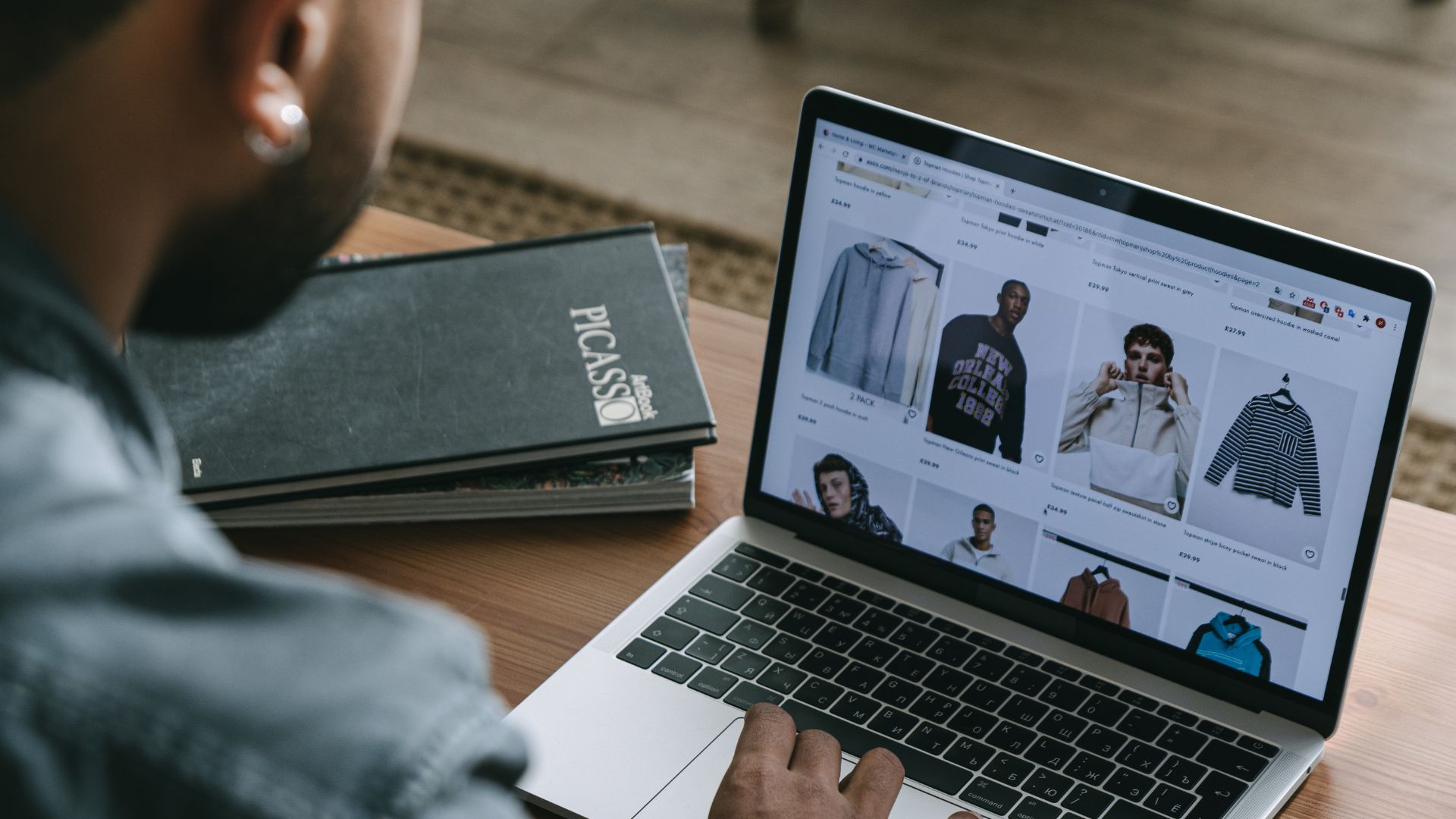 a rear view of a marketer viewing their online clothes store on a laptop